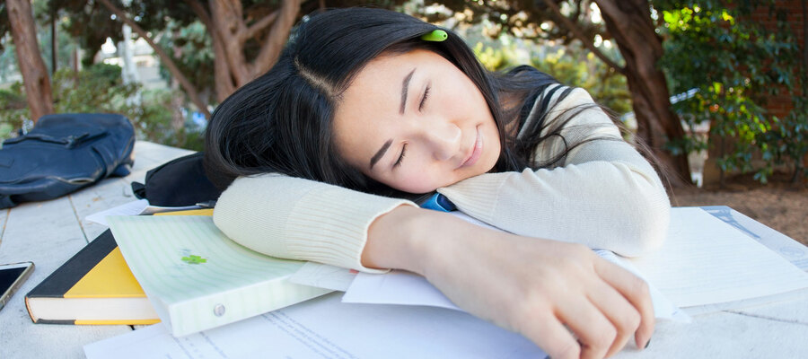 Student sleeping on a pile of books